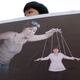 Un manifestante sostiene una pancarta con una imagen de Choi Soon-Sil manipulando a la presidenta de Corea del Sur como si fuera un títere. Foto: AP Images.